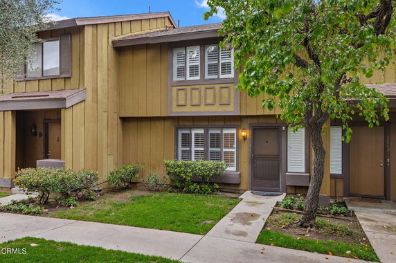 Front view of a two-story townhouse with a brown exterior and small garden area.