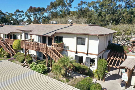 Front view of a two-story residential building with external wooden staircases and balconies.