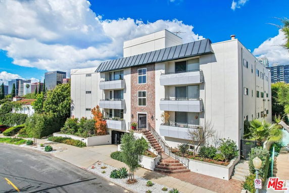 Front view of a multi-story apartment building with a modern design and balconies.