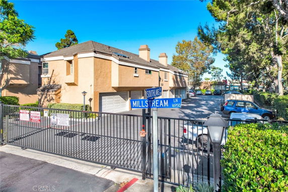 Front view of a two-story residential building with a gated entrance and parking area.