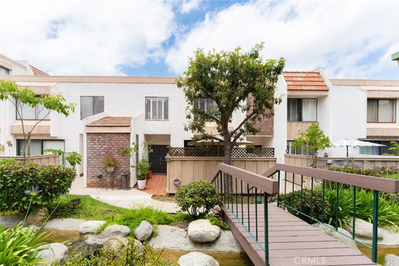 Front view of a townhouse with a pathway and a small wooden bridge leading to the entrance.