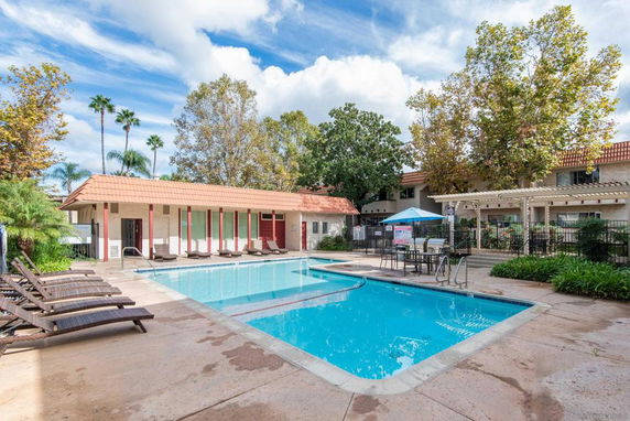 Outdoor swimming pool area with deck chairs and landscaping.