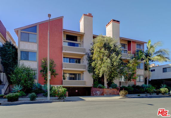 Front view of a multi-story apartment building with a red and beige exterior.