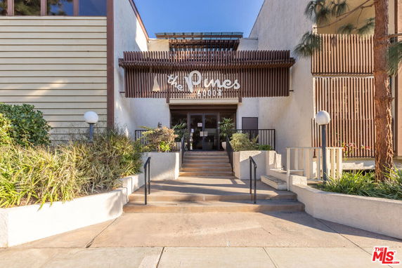 Front view of a building entrance with stairs and a sign reading 'The Pines'.