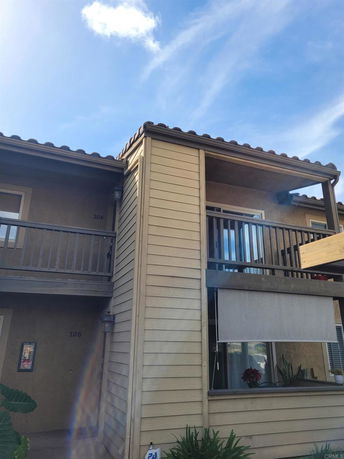 Front view of a two-story residential building with balconies and wooden siding.