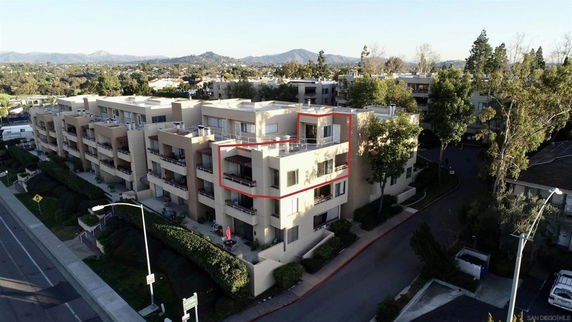 Aerial view of a multi-story residential building with balconies and nearby greenery.