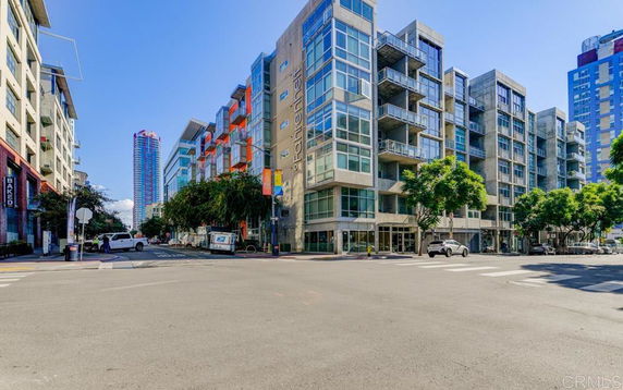 Street view of a modern apartment building with balconies and large glass windows.