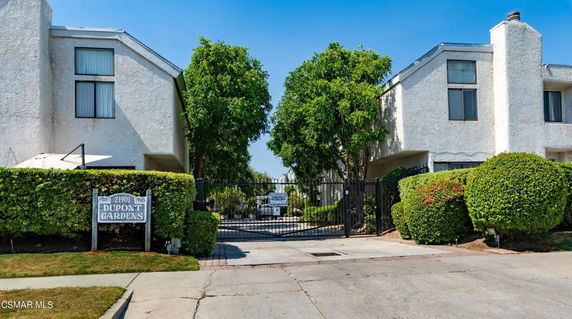 Front view of a multi-story building with gated entrance labeled Dupont Gardens.