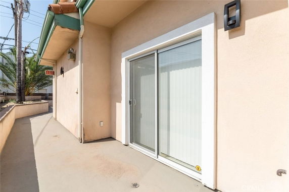 Exterior view of a beige building with a sliding glass door under an overhanging roof.