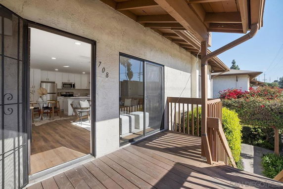 Wooden porch and sliding doors of a house with visible foliage.