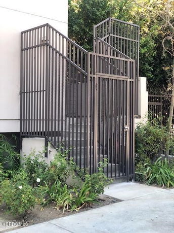 Exterior view of a building with a metal staircase enclosed by a fence.