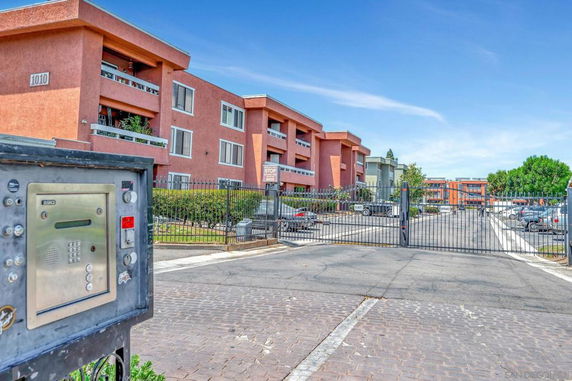 Front view of a multi-story apartment building with a gated entrance.