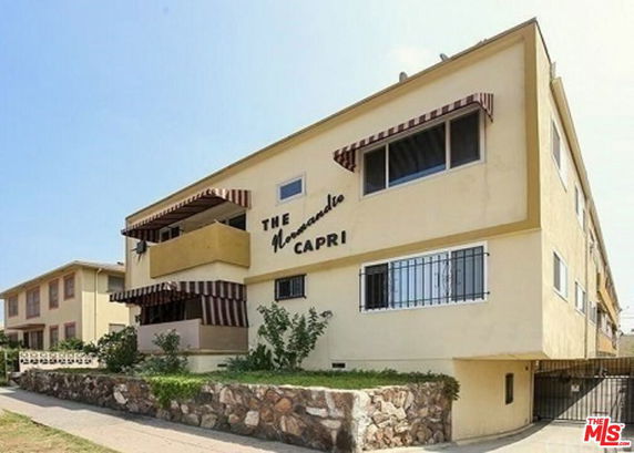 Front view of a multi-story building named 'The Normandy Capri' with striped window awnings.