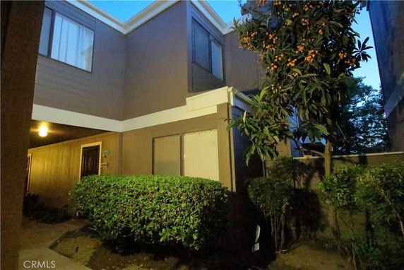 View of a two-story residential building with windows and a small tree.