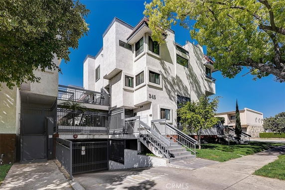 Front view of a multi-story apartment building with balconies and a gated entrance.
