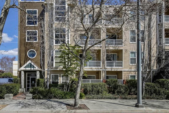 Front view of a multi-story residential building with balconies and large windows.