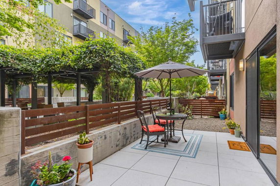 Outdoor patio view with seating area, adjacent to apartment buildings.