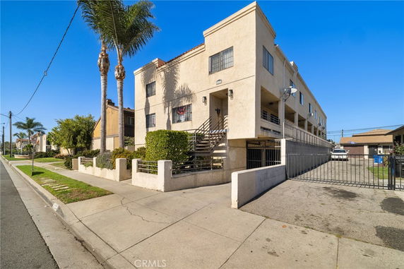 Front view of a multi-story building with a gated entrance and exterior stairs.