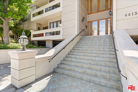 Entrance to a multi-story building with stairs and balcony.