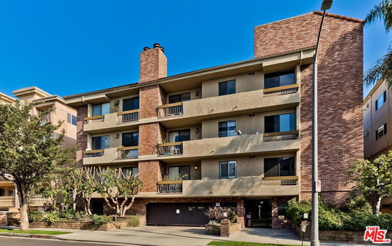 Front view of a multi-story residential building with balconies and brick facade.