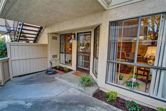 Front view of a residential unit with large windows and a small patio area.