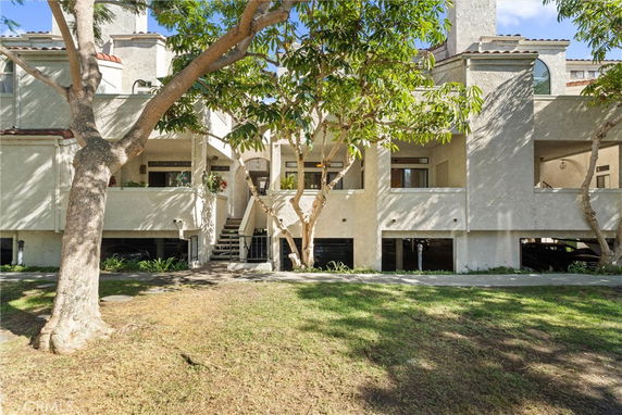 Front view of a multi-story residential building with balconies and covered parking.