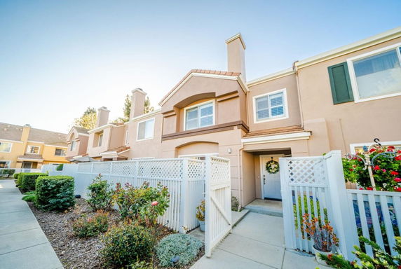 Front view of a two-story townhouse with a gated entrance and small garden.
