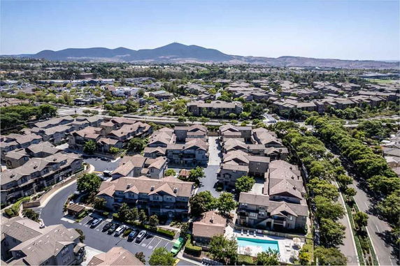 Panoramic aerial view of a residential neighborhood with several houses and a swimming pool.