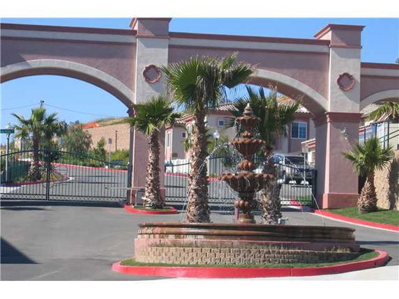 Front view of a gated entrance with decorative arches and a fountain.