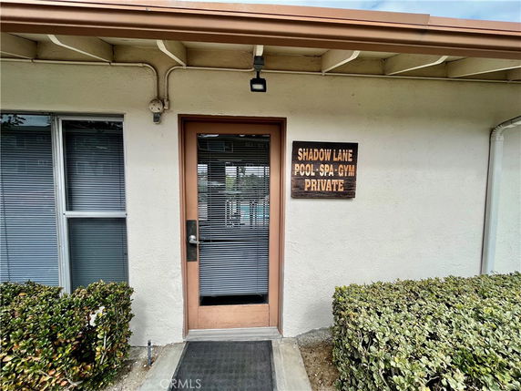 Exterior view of a building entrance with a door and sign indicating pool, spa, and gym facilities.