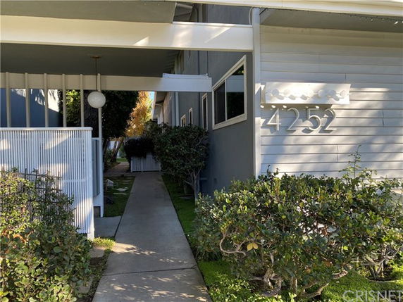 Front view of a building entrance with pathway and address number on the wall.