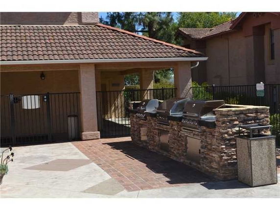 Outdoor area with built-in grills and a sheltered structure with a tiled roof.