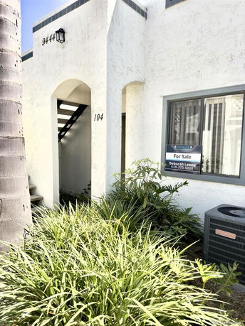 Front view of a white building with an archway and a 'For Sale' sign.