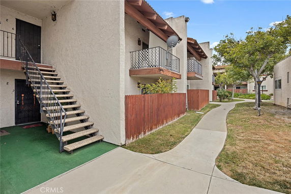 Front view of a multi-level residential building with external stairs and small balconies.