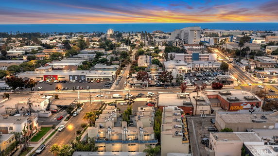 Panoramic view of an urban area with various buildings, roads, and the ocean in the distance.