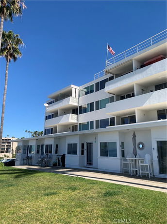 Front view of a multi-story building with balconies and a rooftop flagpole.