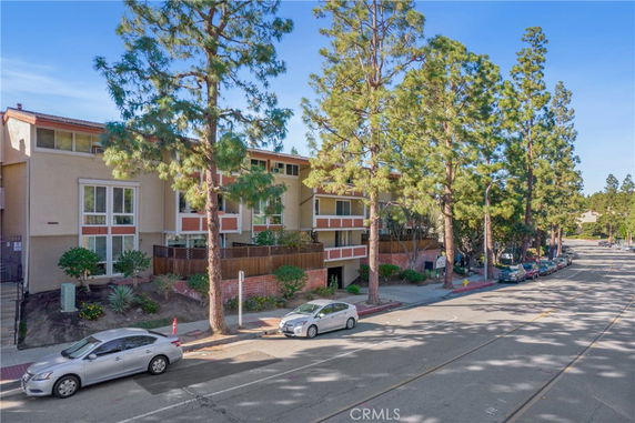 Front view of a multi-story residential building with large windows and a surrounding street.
