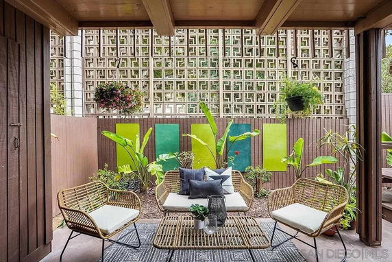 Outdoor seating area with wicker furniture and decorative green plants.