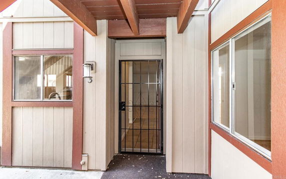 Front view of a building entrance with a metal security door and wooden beams.