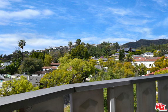 Wide angle view of suburban area with trees and hills in the background.