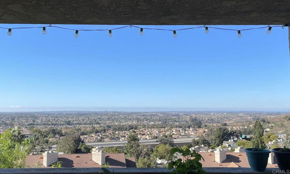 Panoramic view from a building showing an expansive landscape and residential area under a clear blue sky.