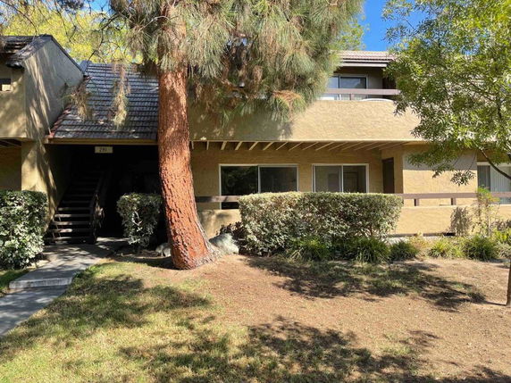 Front view of a two-story building with a tree and shrubs.