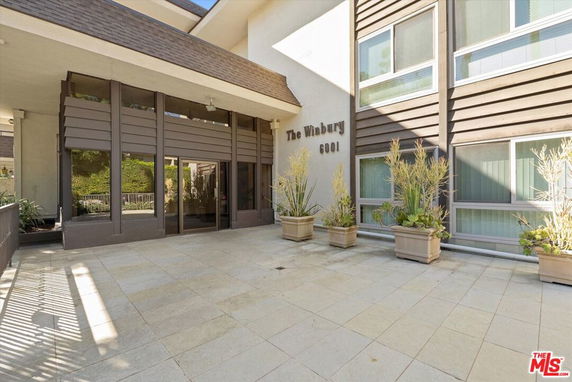 Front view of a building with large windows and potted plants.