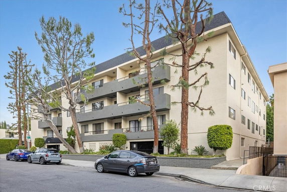 Front view of a multi-story residential building with balconies and a sloped roof.