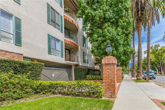 Front view of a multi-story residential building with balconies and a gated entrance.