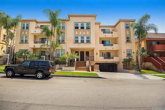 Front view of a multi-story apartment building with balconies and an entrance staircase.