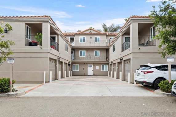 Front view of a three-story residential building with garages on the ground floor and balconies on the second floor.