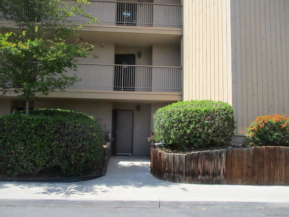 Front view of a multi-story building with balconies and entrance walkway.