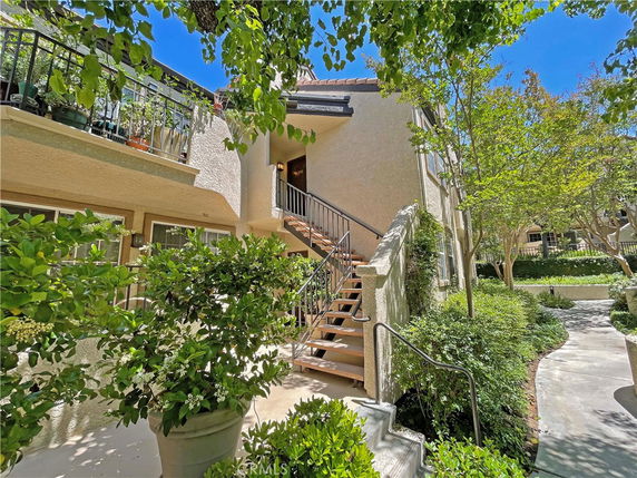Front view of a multi-story residential building with exterior stairs and balcony.