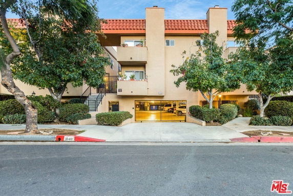 Front view of a multi-story building with a gated parking area.